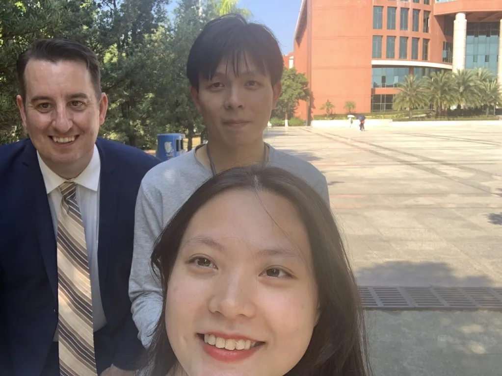 Heath taking a photo with students on campus