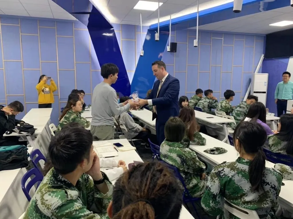 Heath handing a student their certificate at Huashang College
