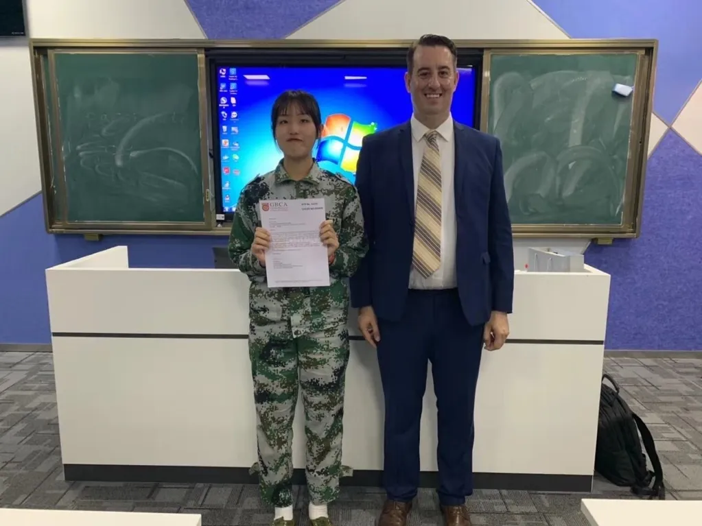 A student proudly holding their certificate with Heath